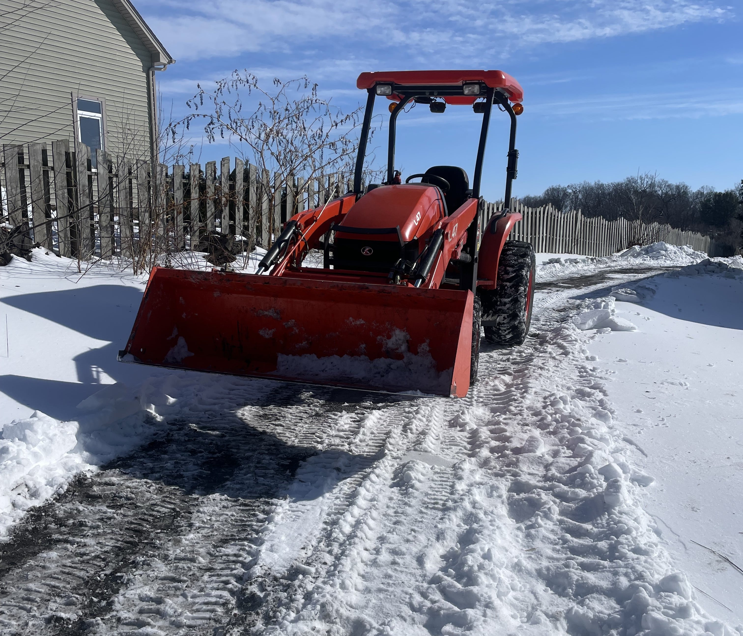 A tractor clearing a neighbor's snowy driveway